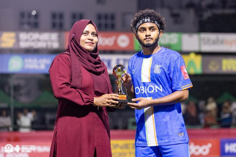 ހިތަދޫއާއި މީދޫ ބައްދަލުކުރިމެޗްގެ މޮޅު ކުޅުންތެރިޔާ އީމާން ނަޒީރަށް ޓްރޮފީ ހަވާލްކޮށްދެއްވި މިމެޗްގެ ޝަރަފްވެރިމެހުމާނާ މީދޫ ކައުންސިލަރު އާމިނަތު ސާލިހާ ފޮޓޯ: ގޯލްޑަންފުޓްސަލް ޗެލެންޖް 2026 ގެ ފޭސް ބުކްޕޭޖުން